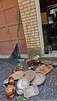 Photo showing full collection of vintage copper and silver plate kitchenware and horn laid out on gravel.
