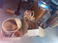 Boxes and baskets containing Wooden serving trays, baskets, plant pots, and various kitchen utensils.