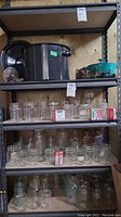 Shelf with large black enameled pot, teal Cuisinart pot, vintage kitchen tools, and shelves full of canning jars and lids