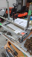 Overall view of aluminum sawmill carriage assembly on table, showing frame, handles and operator’s manual