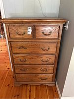 Front view of oak-finish dresser showing five drawers and bail handles, with label on top drawer