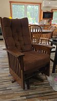 Front angled view showing the full chair with brown tufted back and seat cushions, wood armrests and base.