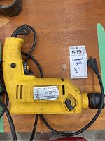 Photo of yellow hammer drill showing side view with power cord and label.