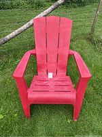 Front view of a red resin lawn chair showing slatted backrest and seat, armrests, and a tag indicating the lot number.