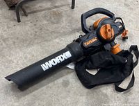 Side view of Worx Trivac leaf blower vac showing brand name and collection bag attached.