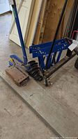 Blue metal shear with a 12-inch blade mounted on a large metal base, showing the full shear and handle.