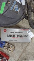 Metal case of Shen Wei ratchet die stock showing brand, size 3/8" to 1 1/4", type NO SWB, and Made in China label