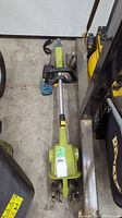 Full view of the green Radley battery garden tiller with charger and battery on concrete floor.