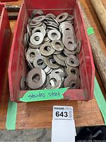 Red plastic container filled with various sizes of flat stainless steel washers labeled as stainless steel.