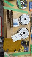 Photo showing two rolls of Linde .035 inch MIG aluminum welding wire, metal wire brushes, and the cowhide helmet bib.