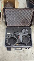 Top-down view of open carrying case showing foam interior with torch handle, cable, spool adapter and cutouts