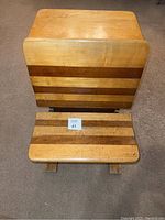 Front view of desk top and seat showing alternating dark and light wood slats and overall rectangular shape.