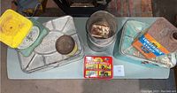 Overview of both Empeco metal bread boxes, Lumbrex and coffee tins, placed on table with scale and wax can