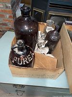 Photo of dark amber Purex brand bottle/jug with embossed lettering plus other amber and clear bottles in a box
