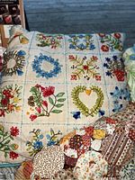 Close-up of decorative pillow with embroidered floral and heart designs