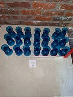 21 cobalt blue goblets arranged upright in 3 rows on table against brick wall
