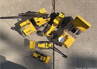 Top view of all five vintage Tonka construction toys arranged on concrete, showing size variation and overall condition.