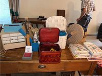Wide view of sewing items on table including woven baskets, thread, and a sewing pattern stack