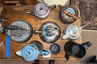 Top view showing various metal pots with different shapes and finishes on a wooden table.
