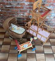 Full view of vintage doll toys including wicker baby buggy, wooden high chair, and giraffe ride-on toy