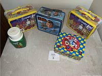 Image showing all four metal lunch boxes and a Scooby Doo thermos on a surface.