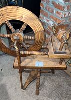 Side view of the entire spinning wheel showing the hand crank, wheel spokes, and three sturdy legs with turned detailing.