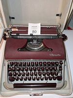 Front view of vintage Olympia typewriter showing keyboard and platen with MaxSold lot number card.