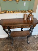 Front view of ornate console table with decorative accents on top shelf