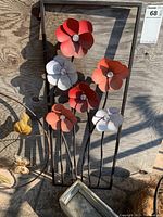 Close-up photo showing six metal flower stakes attached to a black metal rectangular frame.
