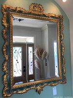 Full front view of carved gilt wood mirror against wall
