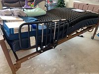 Full view of electric bed frame on casters with alternating bubble overlay and side rails