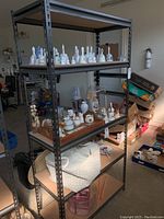 Full view of metal storage shelf with wooden shelves, shelving unit is empty except for some items placed on shelves which are not included.