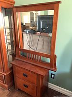 Front view of wooden bedside table with two drawers and matching wooden framed mirror showing overall condition and furniture details.