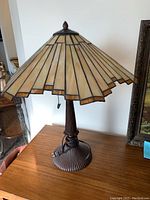 Photo showing the full Tiffany style table lamp with stained glass shade and metal base on wooden surface.