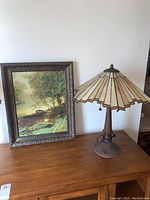 Photo showing Tiffany style table lamp next to the framed artwork on a wooden surface