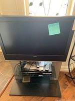 Toshiba TV on a black glass stand with a DVD player and two remote controls visible