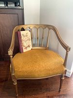 Front angled view of vintage gold framed chair with mustard velvet cushion and decorative backrest showing minor wear.