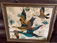 Single photo of quilted fabric bird artwork in ornate wooden frame.