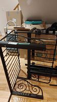 Metal single bed frame disassembled and leaning against boxes, showing decorative metal scrollwork and side rails with slats