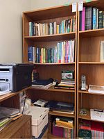 Photo showing the full bookcase filled with books and other office items, highlighting the wood laminate finish and adjustable shelves.