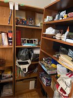 Bookcase shown with personal items for scale and context, including books, photo frames, hobby items, and board games such as Monopoly and puzzles.