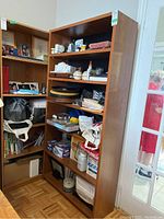 Front right angled view showing full height bookcase packed with miscellaneous items on shelves.