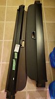 Two black cargo covers for BMW X5, showing retractable mechanism and handles