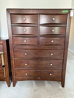 Front view of wood tall boy dresser showing 9 drawers with metal knobs, dark wood finish.