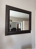 Framed beveled mirror hung on wall reflecting room interior.