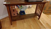 Front side view of the wood sofa table showing rectangular top, slatted vertical side supports and lower shelf.