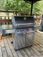 View of stainless steel Weber Genesis grill on wooden deck under canopy