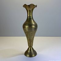 Front view of a brass decorative vase showing its shape and detailed engravings.