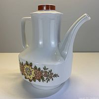 Full view of the teapot showing the floral decoration, handle, spout, and lid.