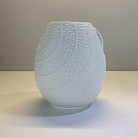 Front view of white oval Kaiser porcelain vase with raised circular radial pattern